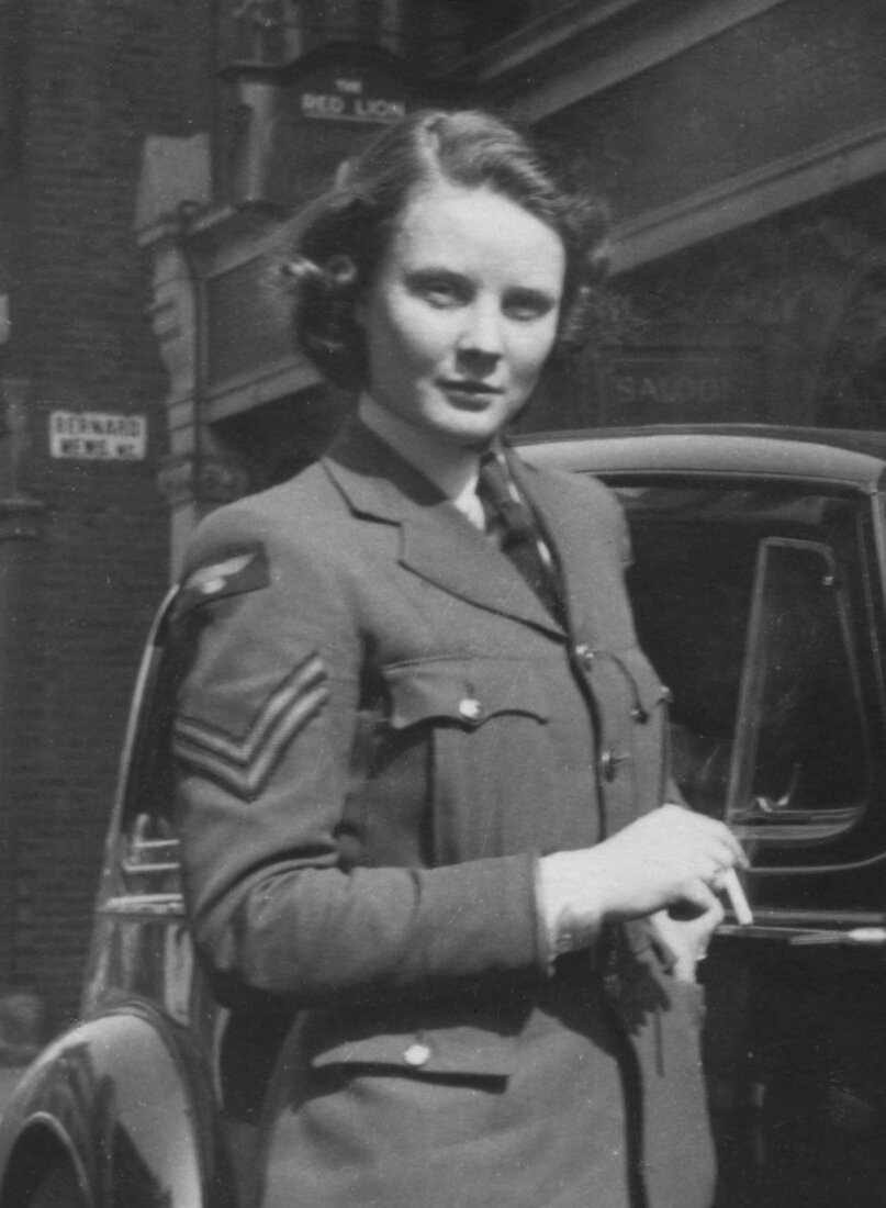 Barbara Mills in WAAF uniform, wearing sergeant’s stripes, beside a staff car in wartime London